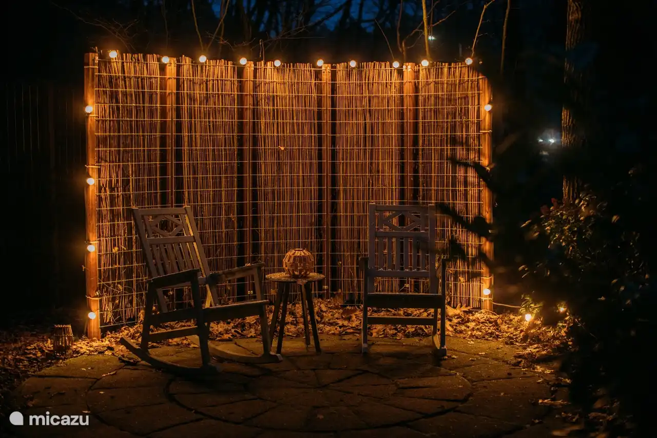 Zona de estar acogedora en el jardín con luz cálida para largas noches al aire libre.