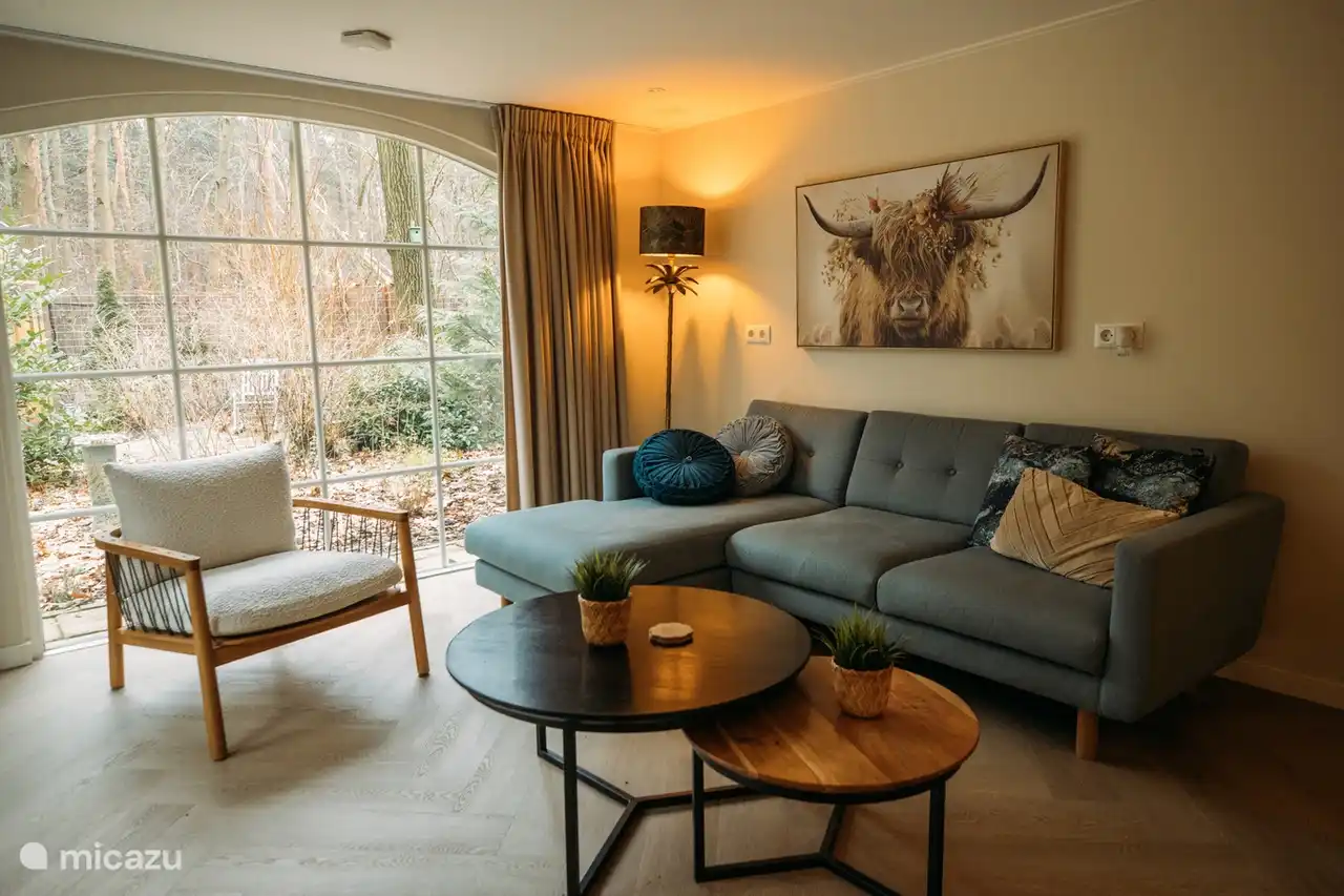 Zona de estar acogedora con vistas al bosque y sofá cómodo.