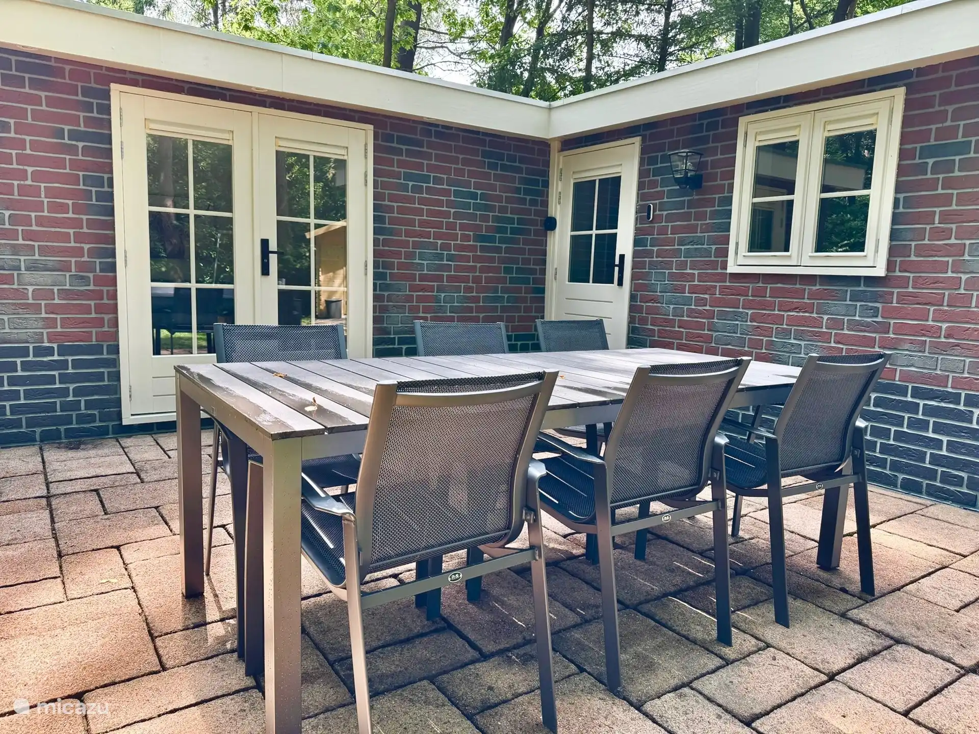 Das Foto zeigt eine gemütliche Sitzecke mit Esstisch auf der Terrasse. Ein perfekter Ort, um gemeinsame Mahlzeiten unter freiem Himmel zu genießen, umgeben von Grün und Ruhe. Ideal für ein gemütliches Frühstück, Grillen oder einen gemütlichen Abend unter dem Sternenhimmel.