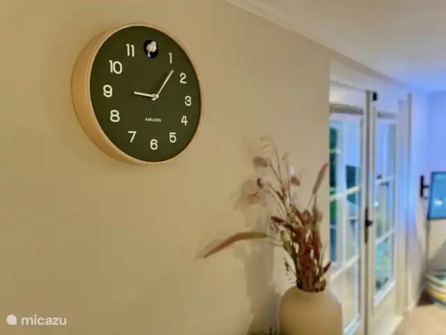Maison de vacances Maridu Family Wellness | Pays-Bas, Gueldre, Hattemerbroek - chalet 
Le mur calme du salon respire la simplicité et la sérénité, avec une horloge à coucou moderne comme détail élégant. L’horloge s’intègre parfaitement au thème naturel de la maison et ajoute une touche ludique et contemporaine à l’atmosphère détendue.