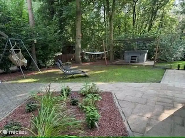 Maison de vacances Maridu Family Wellness | Pays-Bas, Gueldre, Hattemerbroek - chalet Le jardin offre une image complète de la détente et de la nature, avec le hamac et le hamac entre les arbres au premier plan et le luxueux bain à remous en arrière-plan. Un endroit parfait pour profiter de la tranquillité entourée de verdure et du doux bruit des oiseaux et des écureuils.