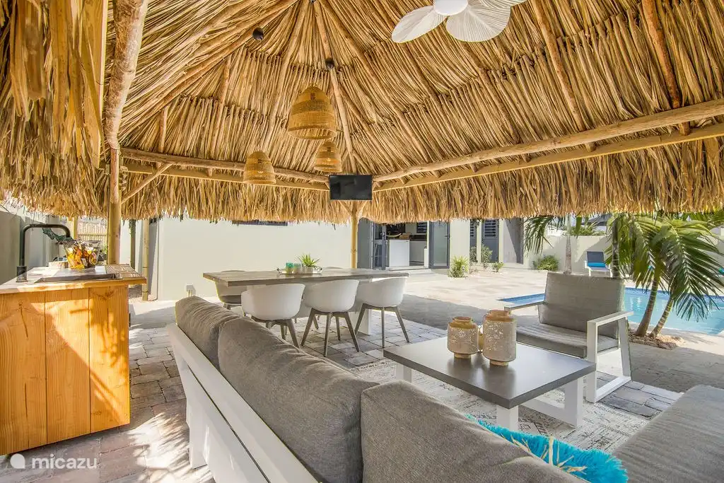 Palapa met loungeset, eettafel, tv en buiten keuken