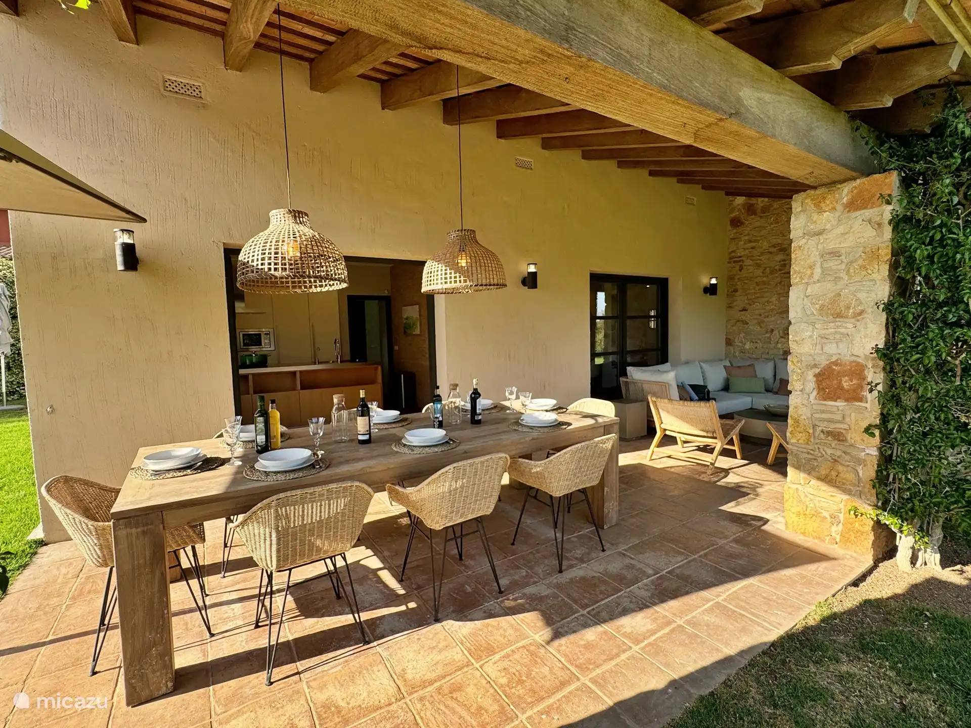 Essbereich im Freien auf der überdachten Terrasse neben der Küche und mit Blick auf den Garten.