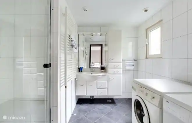 Badezimmer mit Waschtischunterschrank, ebenerdiger Dusche, Waschmaschine und Trockner