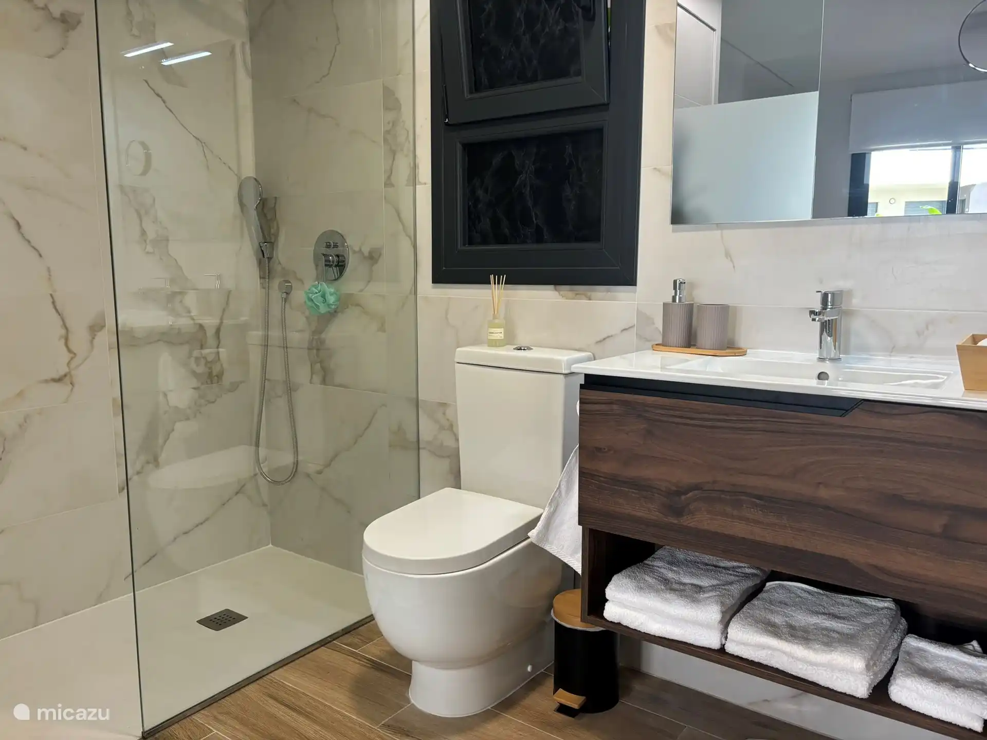 La salle de bain attenante est adjacente à la chambre principale avec une douche à l’italienne spacieuse, des toilettes et un lavabo.