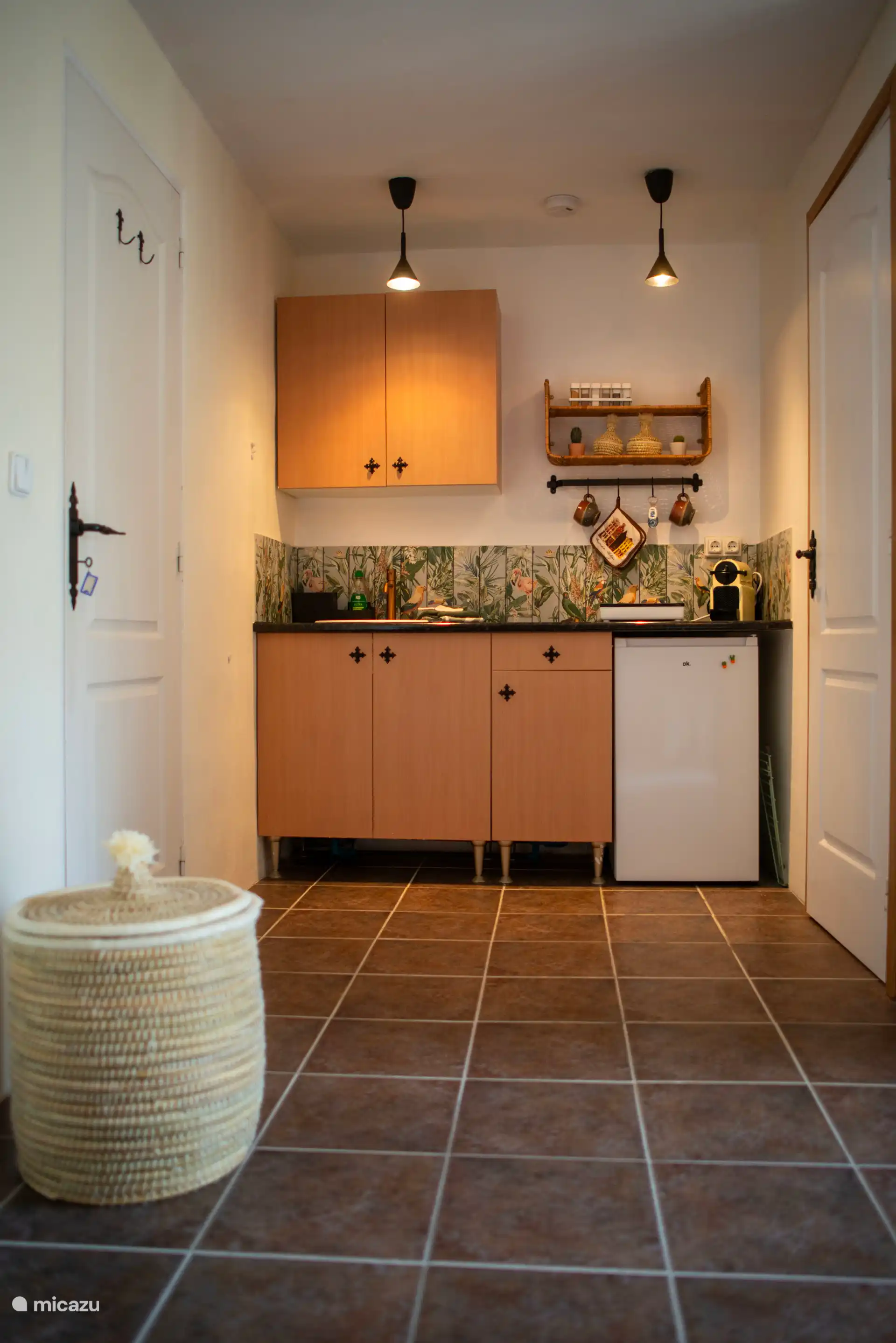 Cocina pequeña con placa de inducción de 2 fogones, cafetera Nespresso y nevera con compartimento congelador