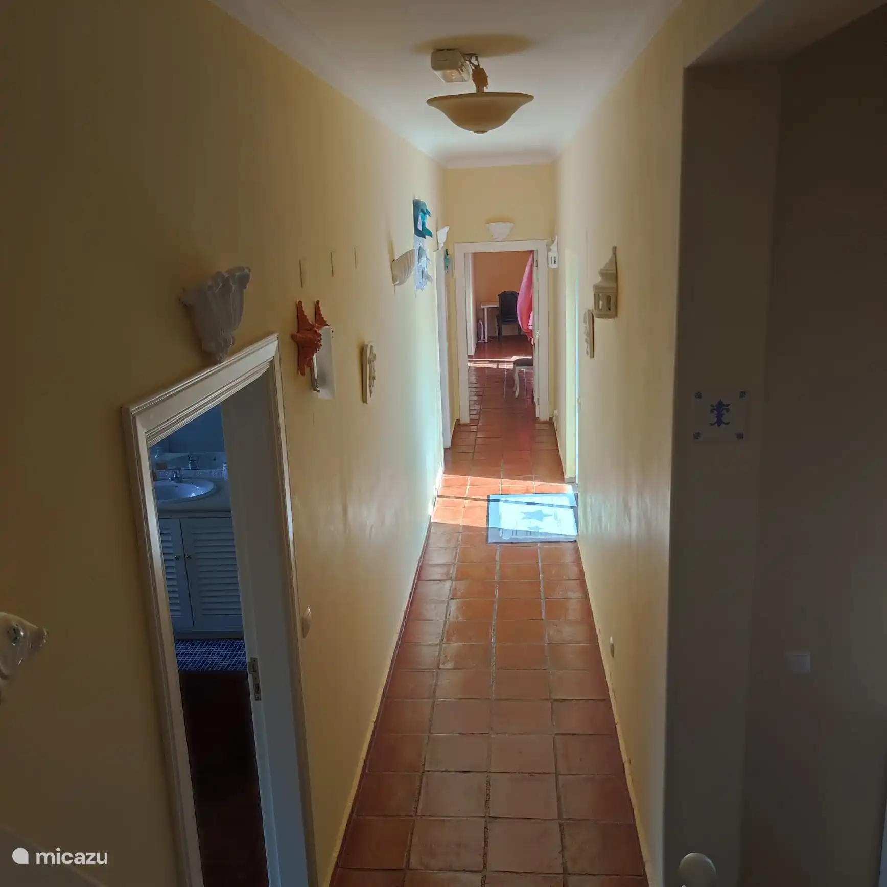 Voici le couloir principal, nous avons deux portes de chambre sur le côté gauche, une chambre au bout du couloir et sur le côté droit se trouve la grande fenêtre qui mène à la piscine. 