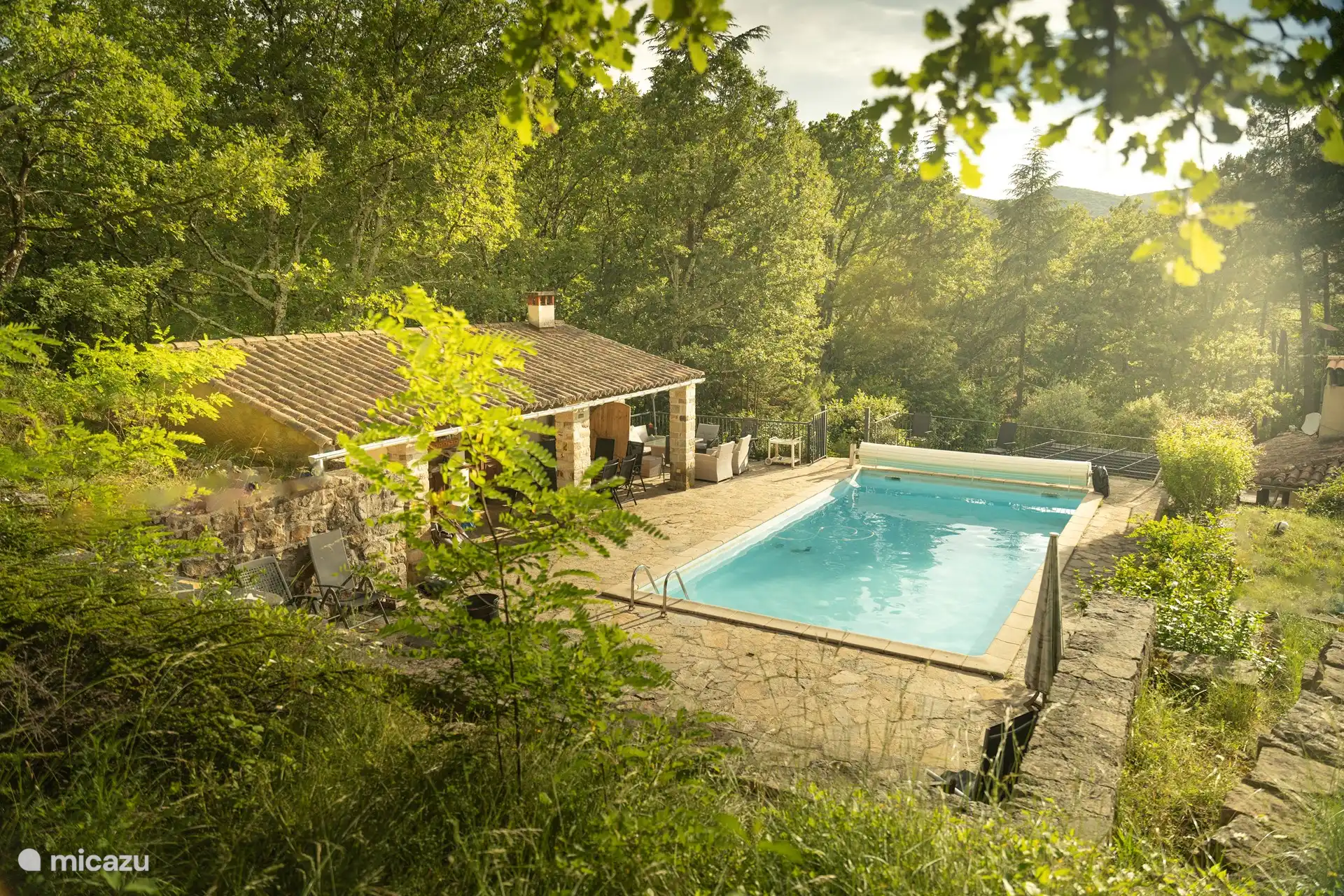 der Poolbereich, ein Zwölfertisch, ein weiterer 6er-Tisch, eine Küche, Kühlschrank, Backofen, WC, Dusche.