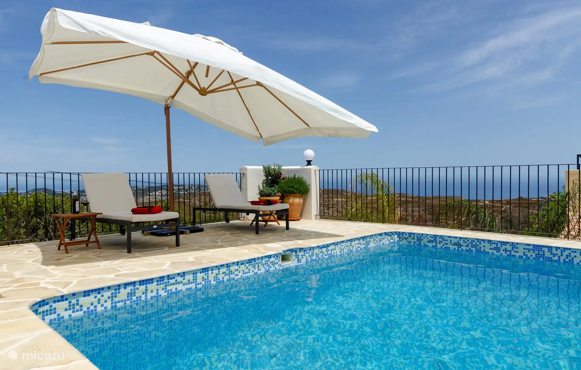 Liegestühle und Sonnenschirm neben dem Pool