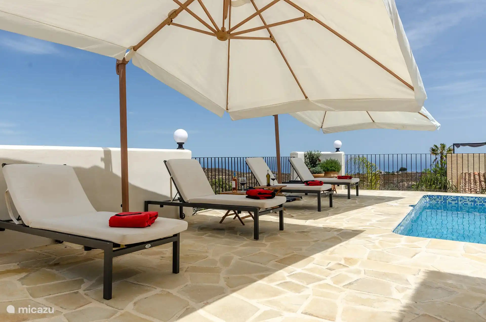 Liegestühle und Sonnenschirm neben dem Pool