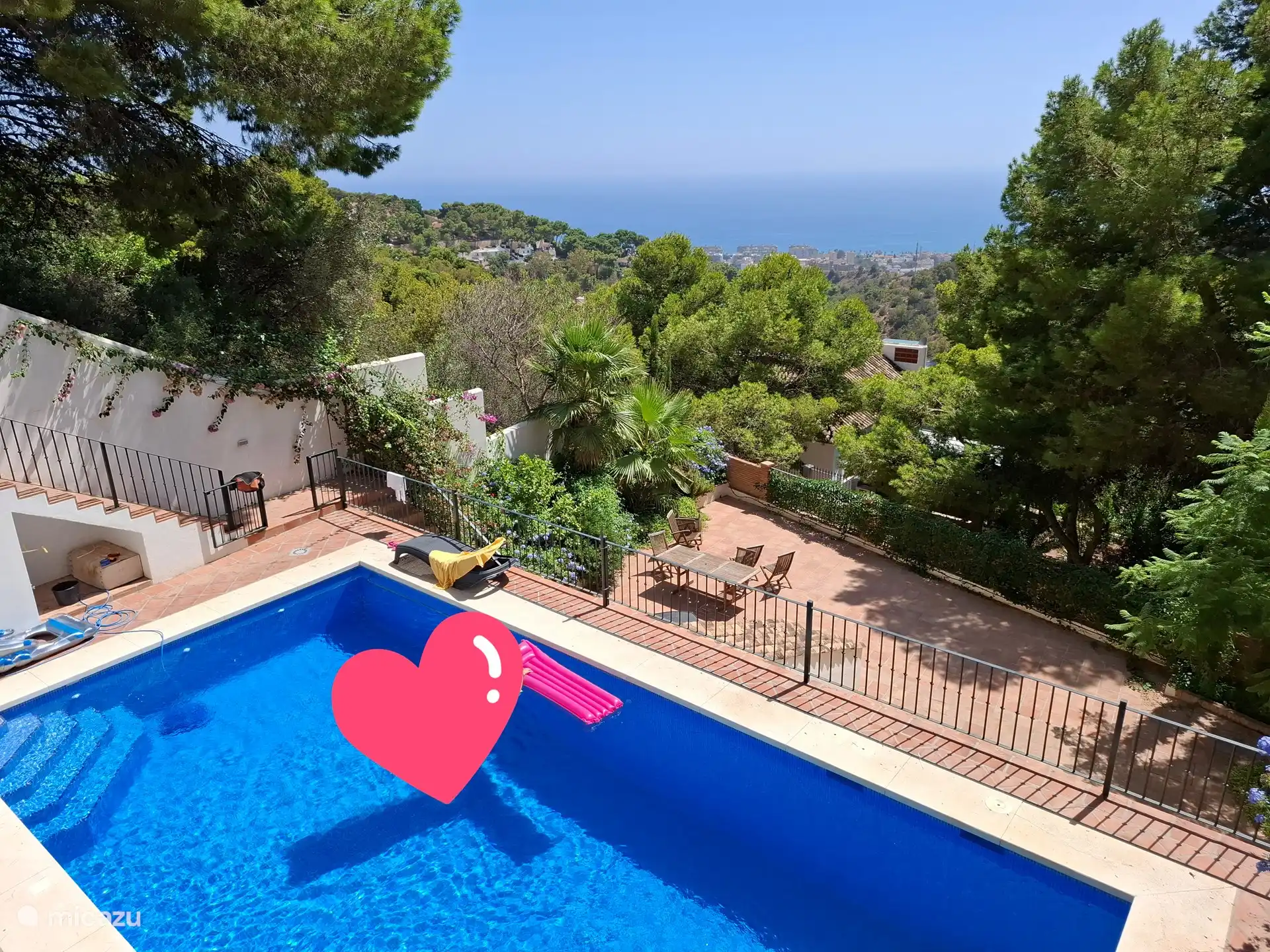 Uitzicht over het zwembad en daaronder het dakterras van het appartement