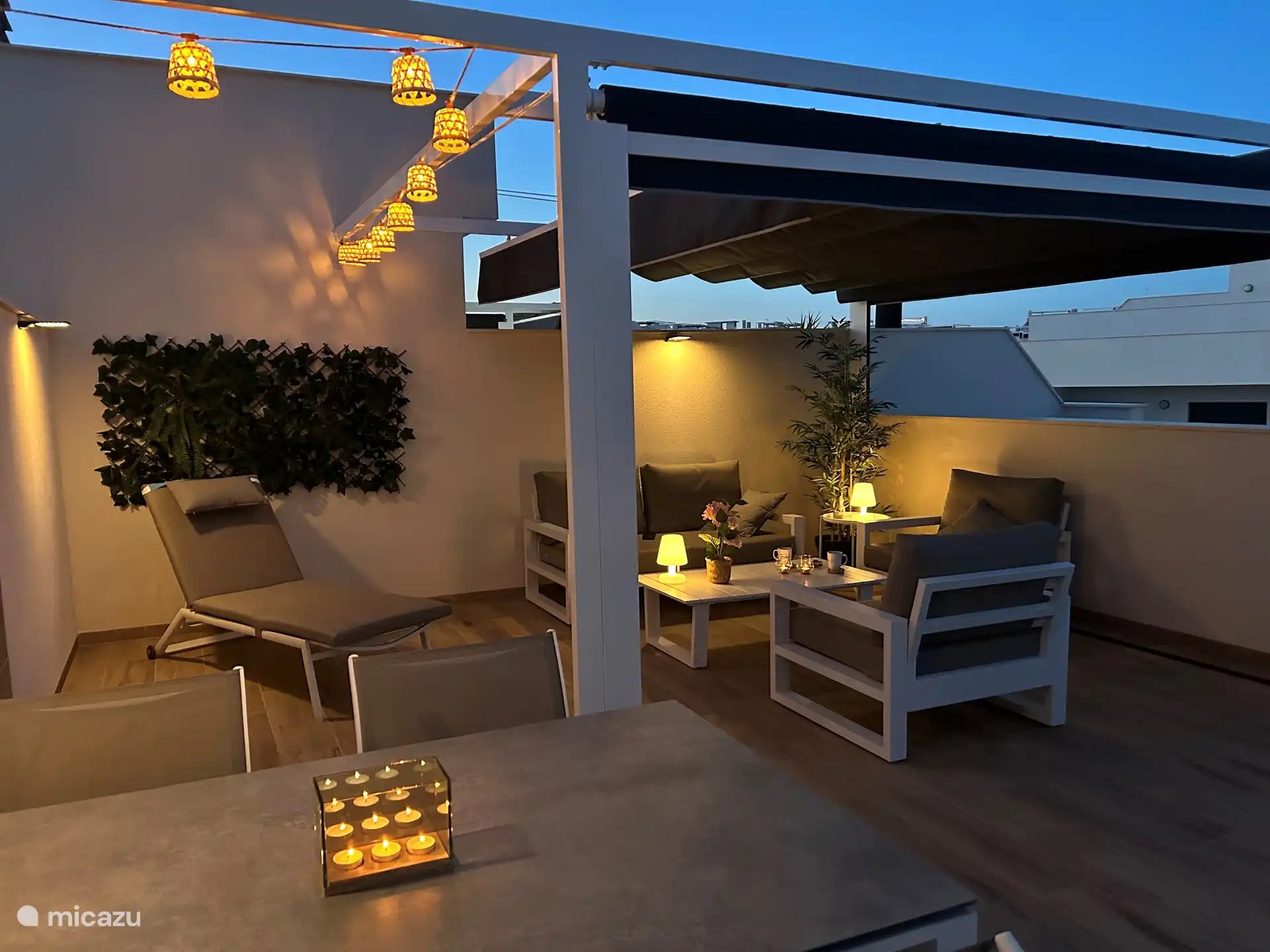 dakterras met een pergola en lounge set in de avond