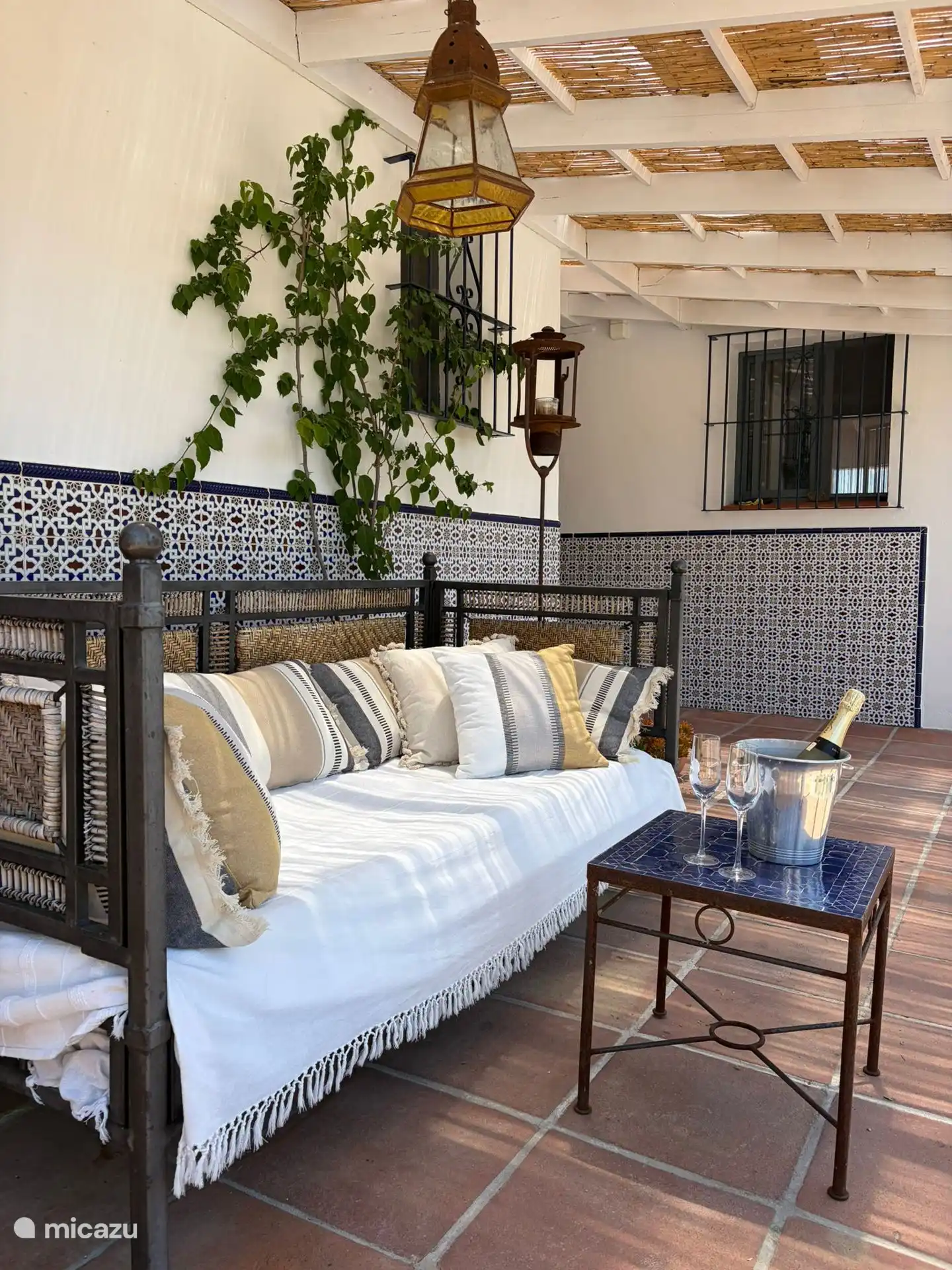 La terrasse couverte avec « lit de jour », à côté de la cuisine, orientée à l’ouest (coucher de soleil et idéal pour un « coucher de soleil » !).