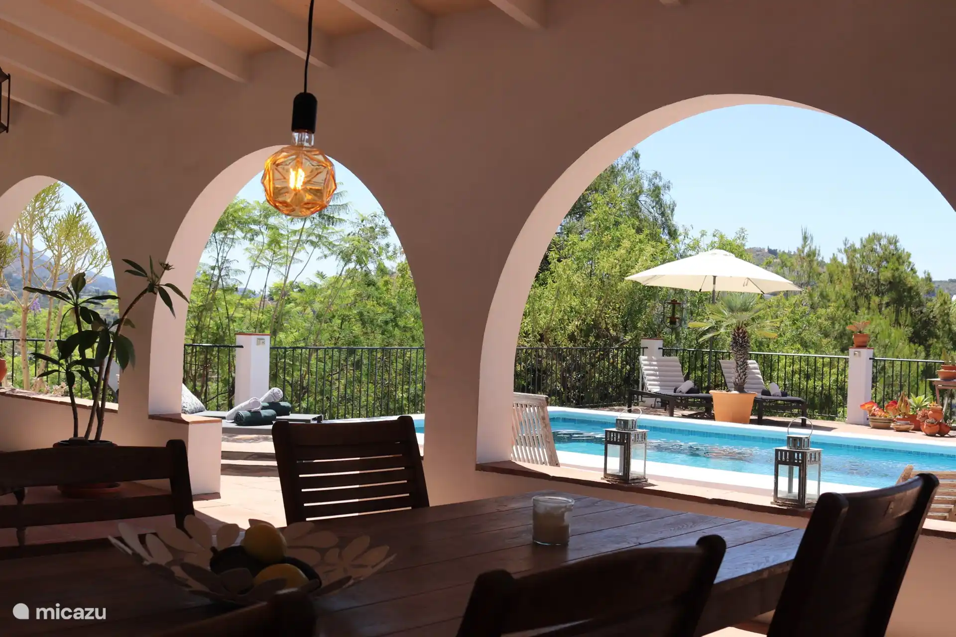 Vista desde la mesa de comedor en la terraza de la terraza. Mucha privacidad, ambiente, restaurantes y empleo. Encima de la mesa del comedor cuelga un ventilador para refrescarse en los días calurosos.