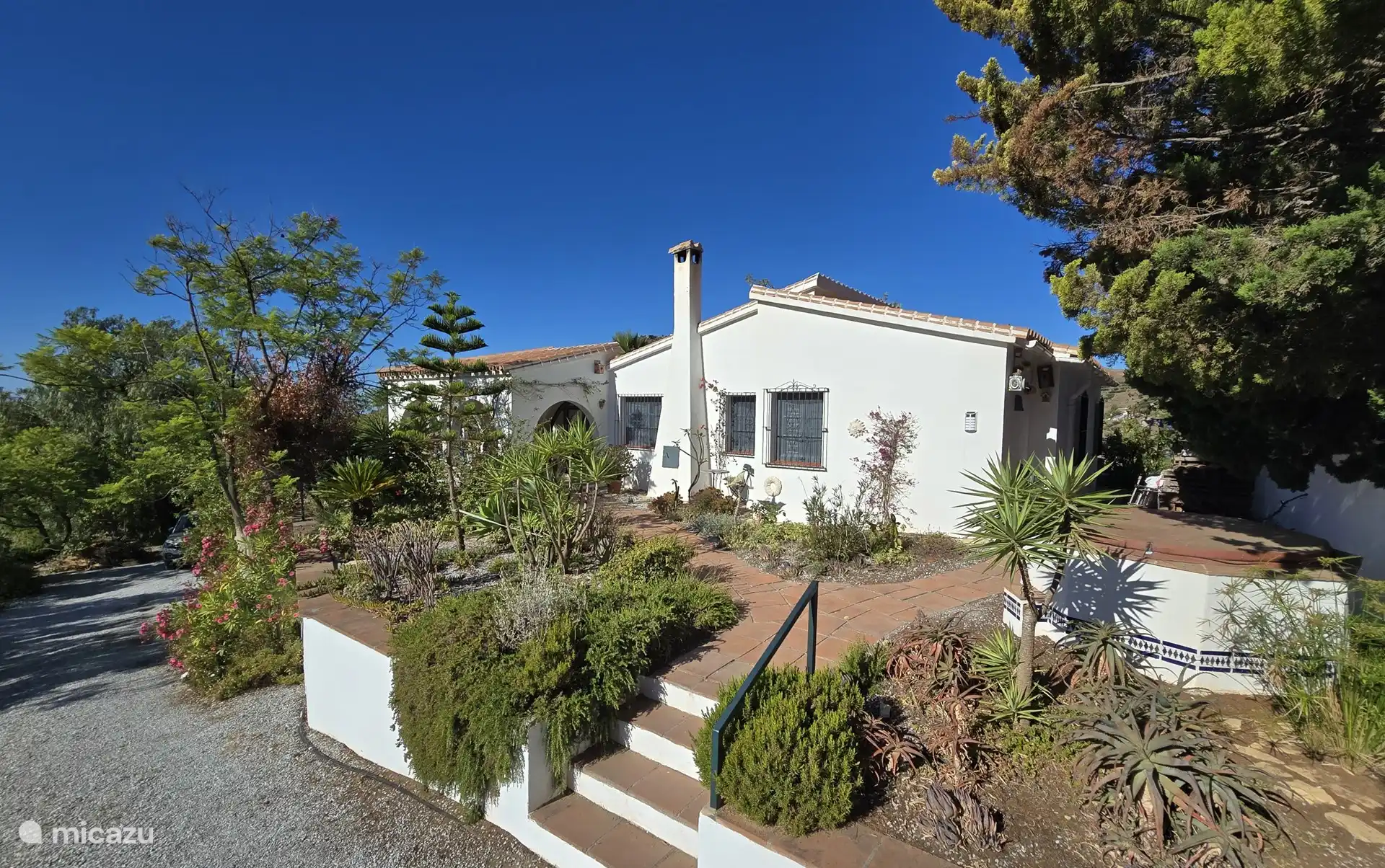 El lado de la casa con el camino del jardín (iluminado) hasta la entrada (lateral) de la casa.