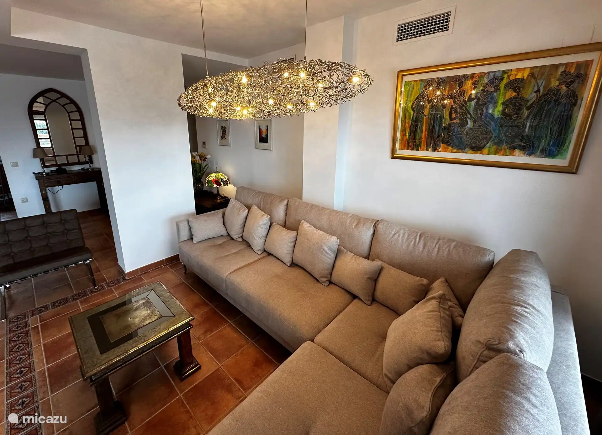 Part of the salon with a spacious sofa and illuminated design lighting by Brand van Egmond.