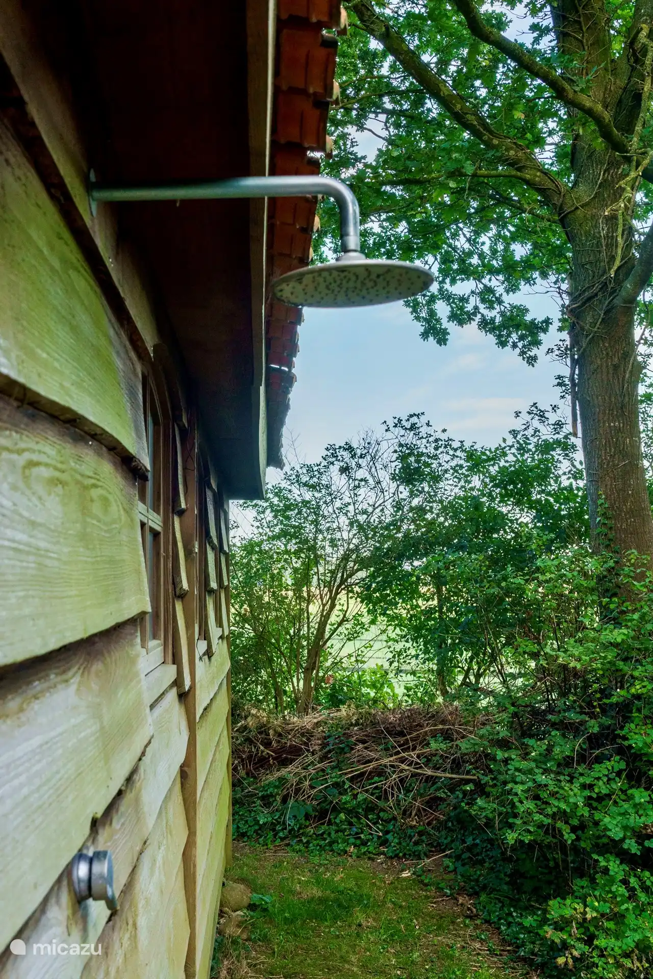 At the rear of the garden house with outdoor shower.