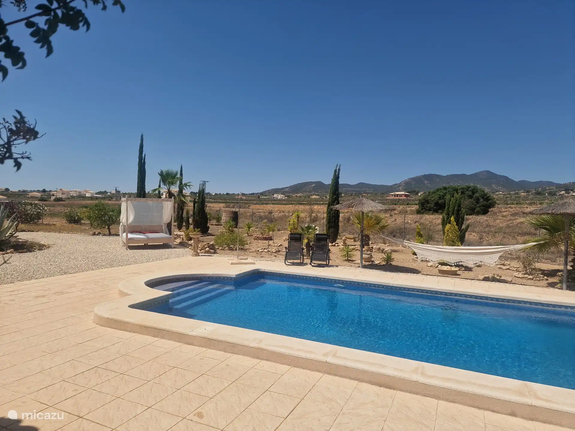 Blick auf den Pool und das Himmelbett von der Poolterrasse
