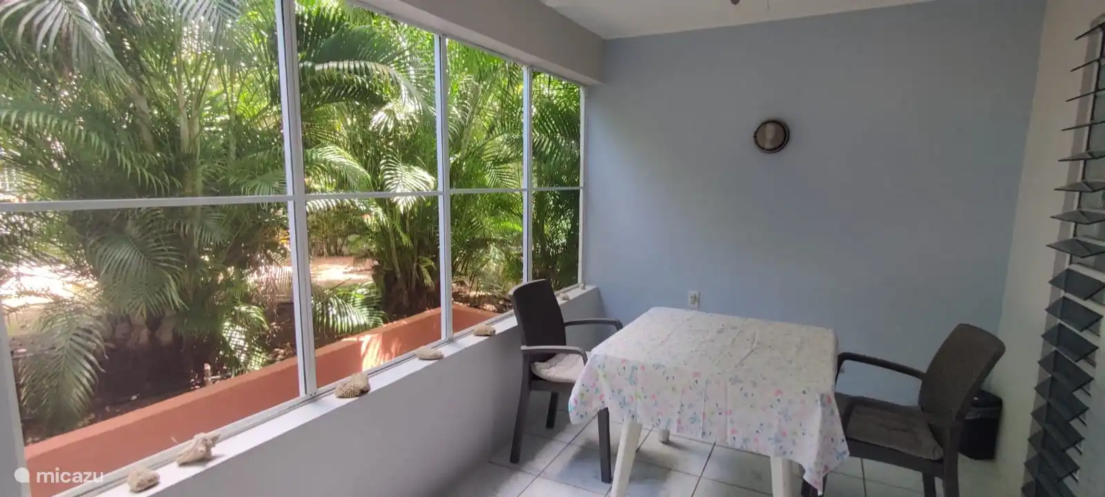 Balcón en la planta baja con asientos y ventanas de mosquitera