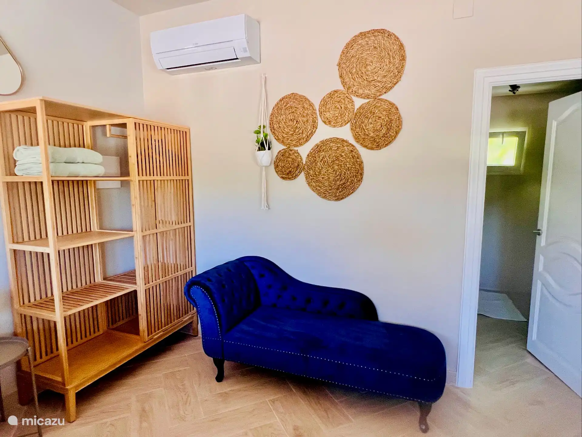 Armario y chaise longue en su habitación, con entrada al baño en suite.