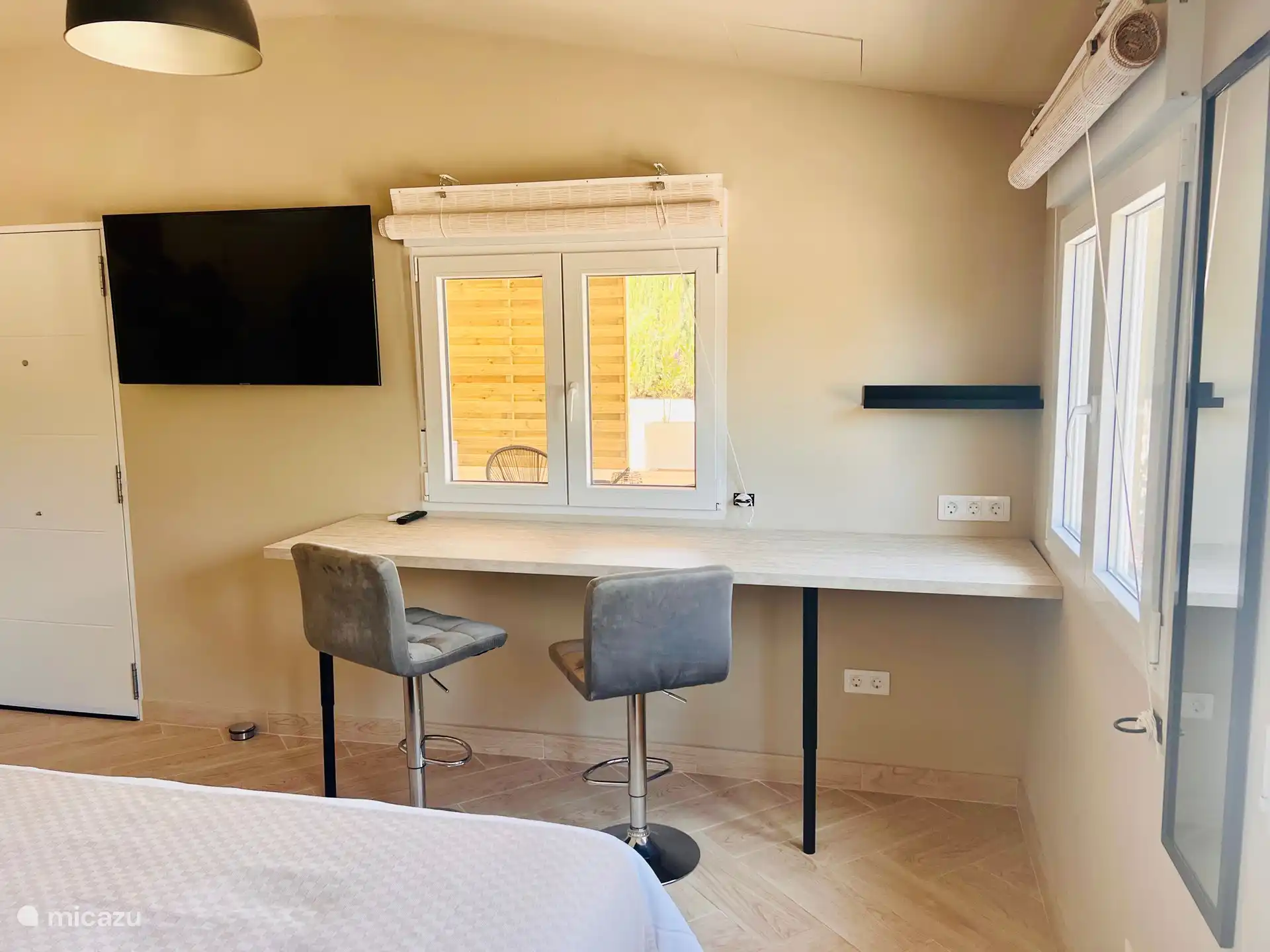 Smart TV grande con Google Chromecast, escritorio largo y alto con 2 taburetes de bar.