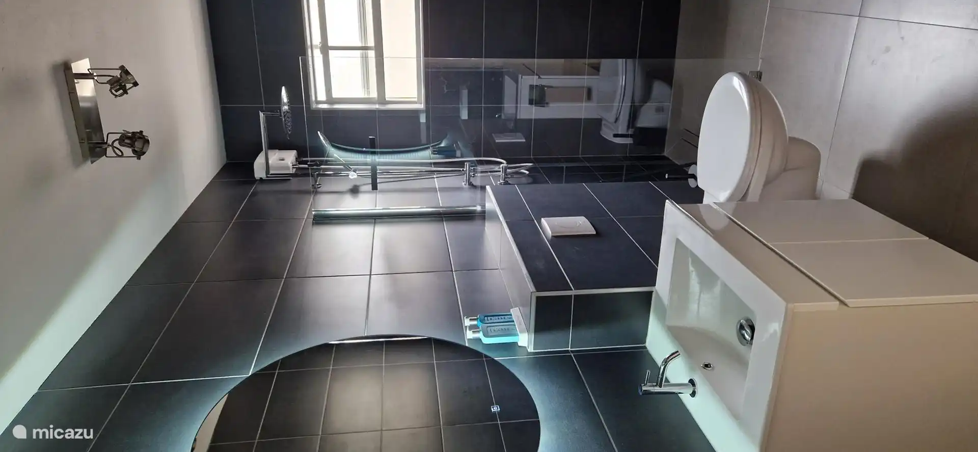 Dieses Badezimmer ist komplett neu und mit einer Regendusche, einem Spiegel mit Beleuchtung, einem Shampoo- und Seifenspender, einer schwimmenden Toilette, einem Waschbecken und zusätzlichen Ablagen zum Ablegen ausgestattet.