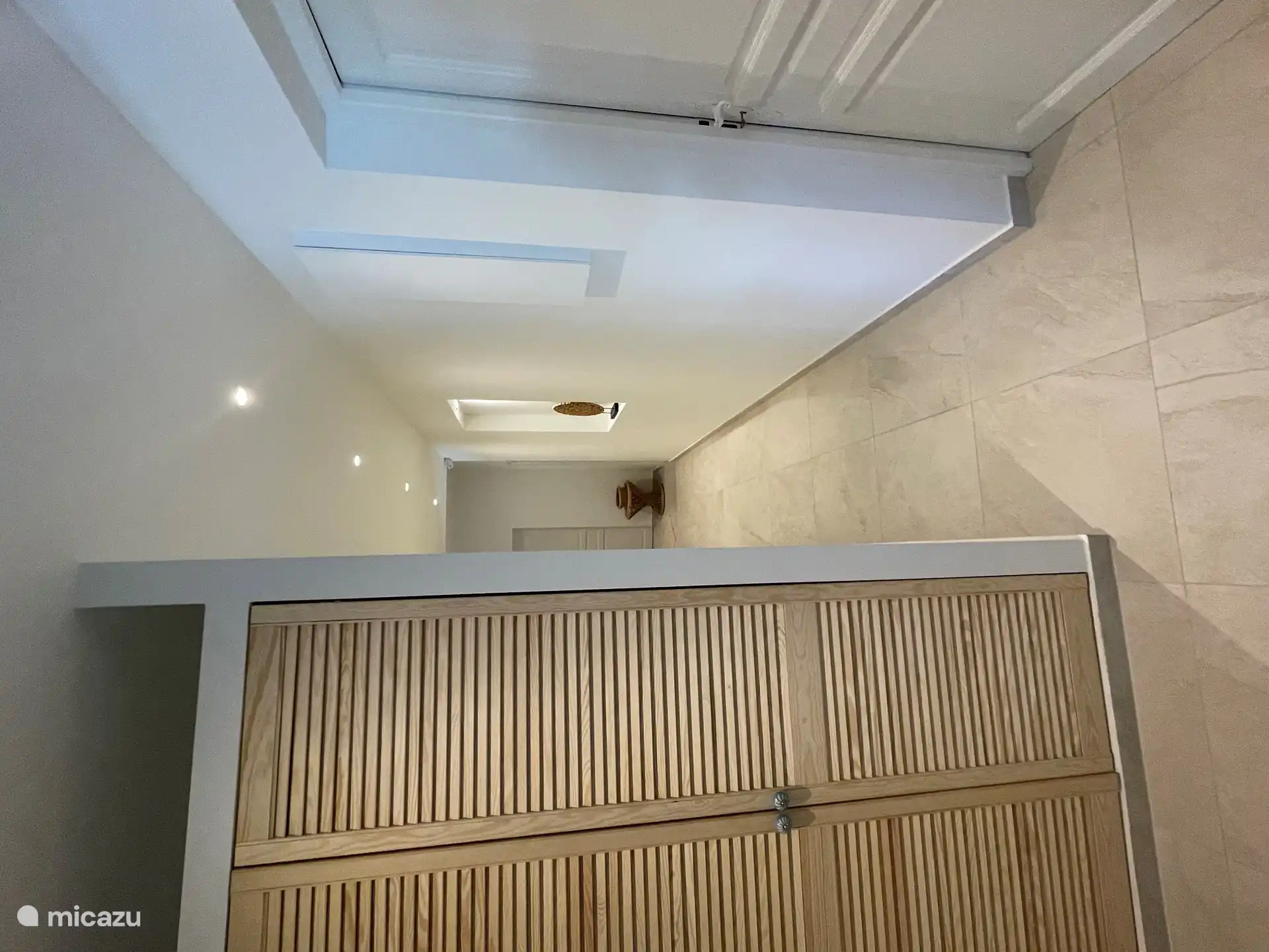 Moderne hal met nisje en kasten met louvre deuren.