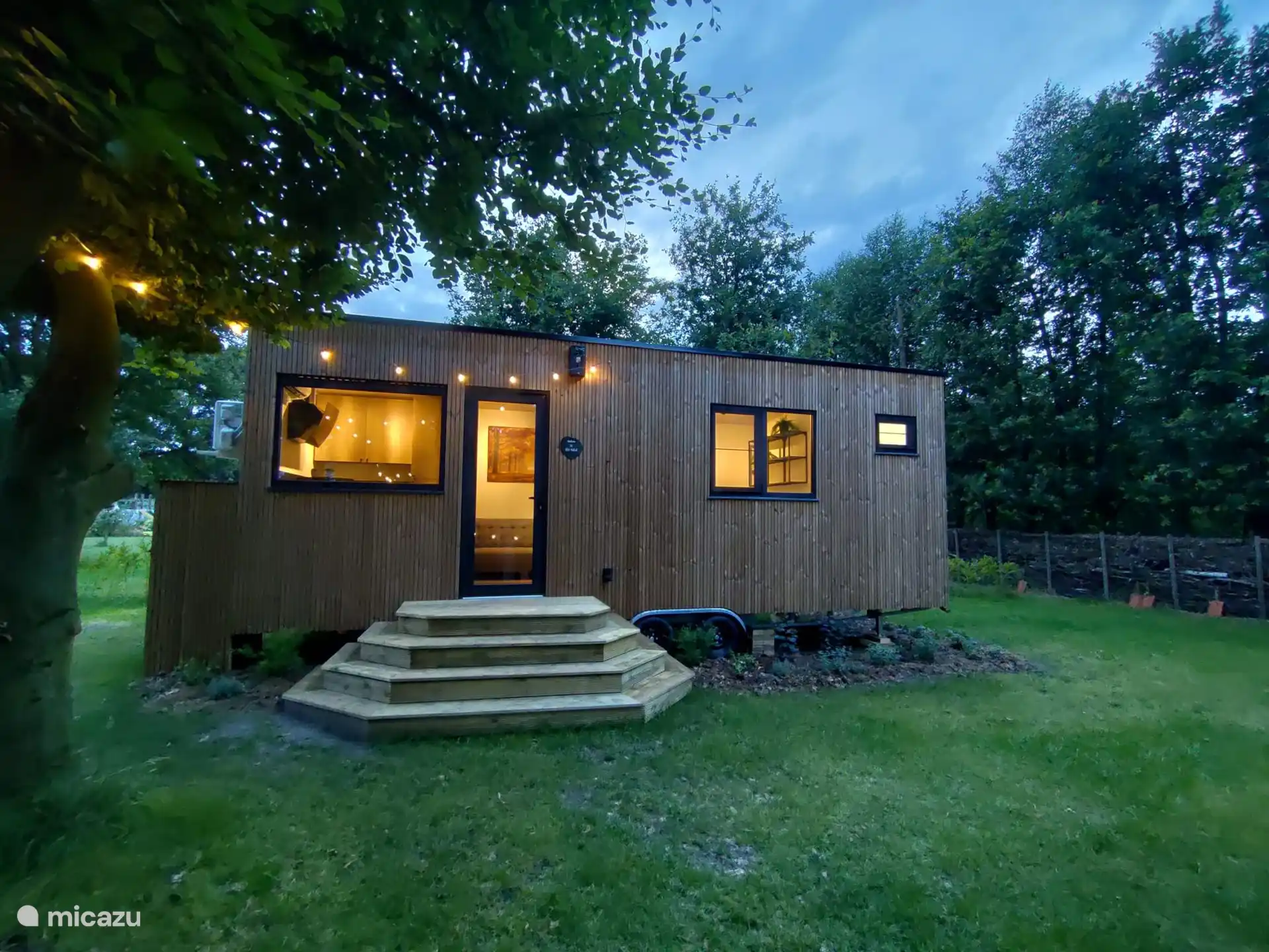 De gezellige buitenkant met een aanpalende tuin te midden van mooie bomen en een omringde takkenwal