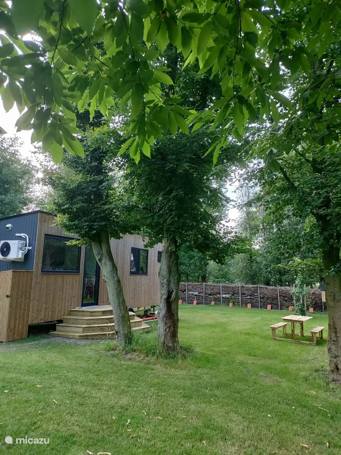 De gezellige buitenkant met een aanpalende tuin te midden van mooie bomen en een omringde takkenwal