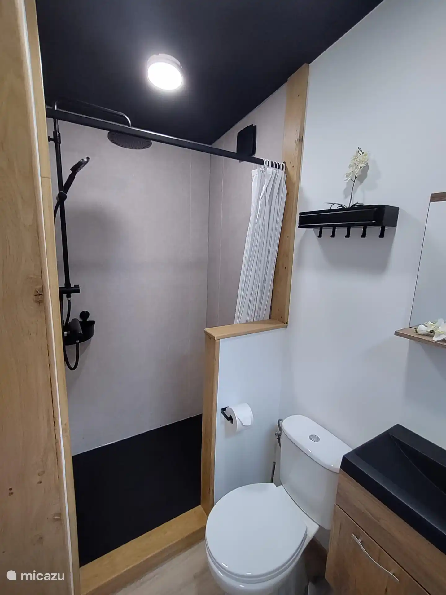 Volledig ingerichte douche met enkele kapstokjes voor de handdoeken aan te hangen.