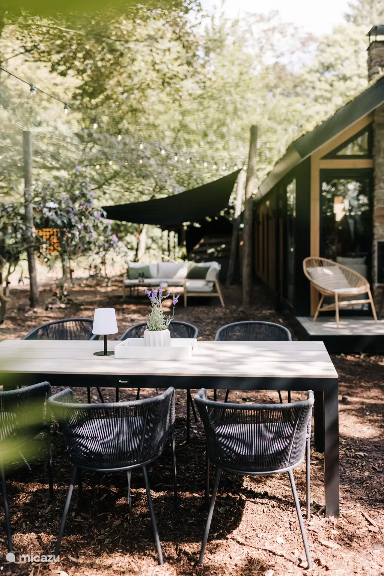 Privat gelegenes Chalet mit Tisch im Freien und Loungebereich, beide mit Blick auf den Wald.