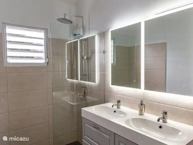 villa huren in Curaçao, Banda Ariba (oost), Marie Pampoen – Indigo House De ruime en moderne master badkamer is voorzien van een extra spiegeltje, fohn, ehbo doos en douche met warm water.