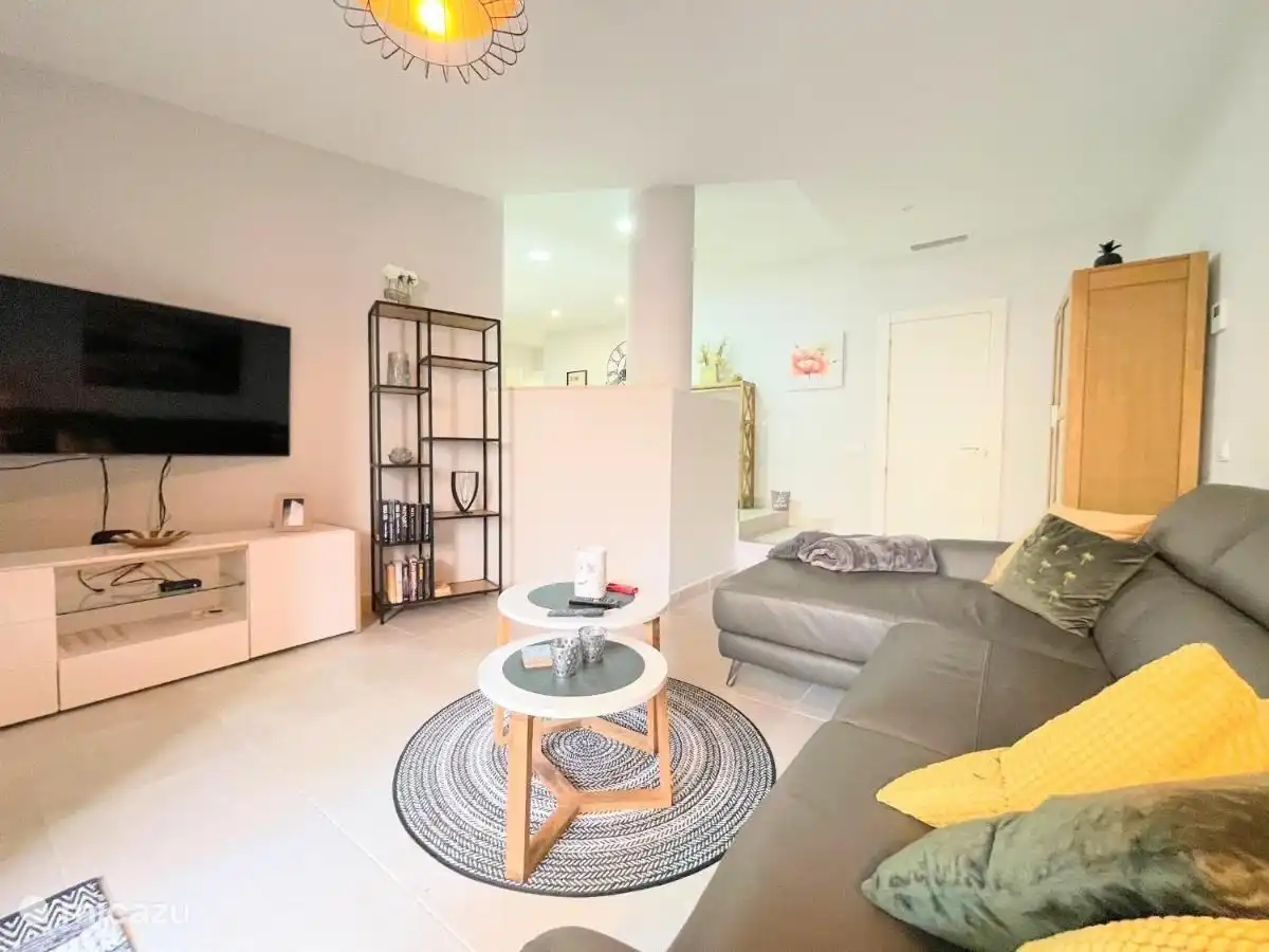 Sala de estar de dos niveles con un sofá grande y un televisor con Chromecast