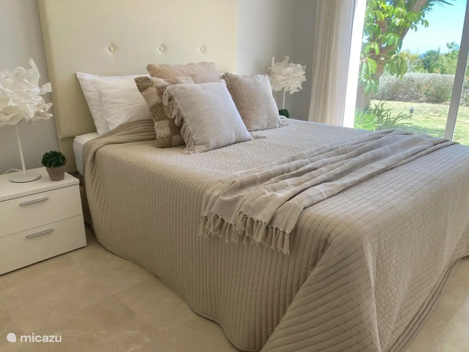 Schönes großes Bett und Blick über den Garten und auf das Meer.