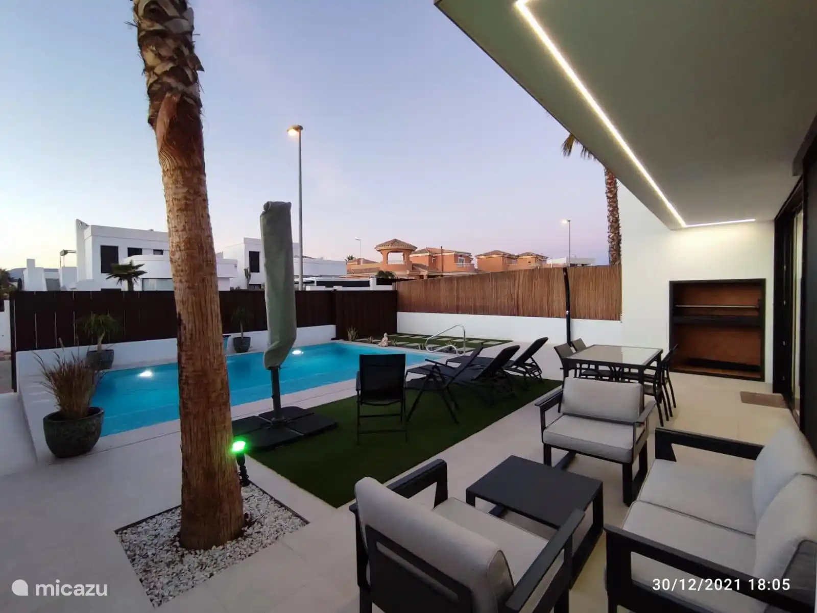 Garten mit Grill, Lounge-Set, Liegestühlen und Esstisch mit Stühlen.
