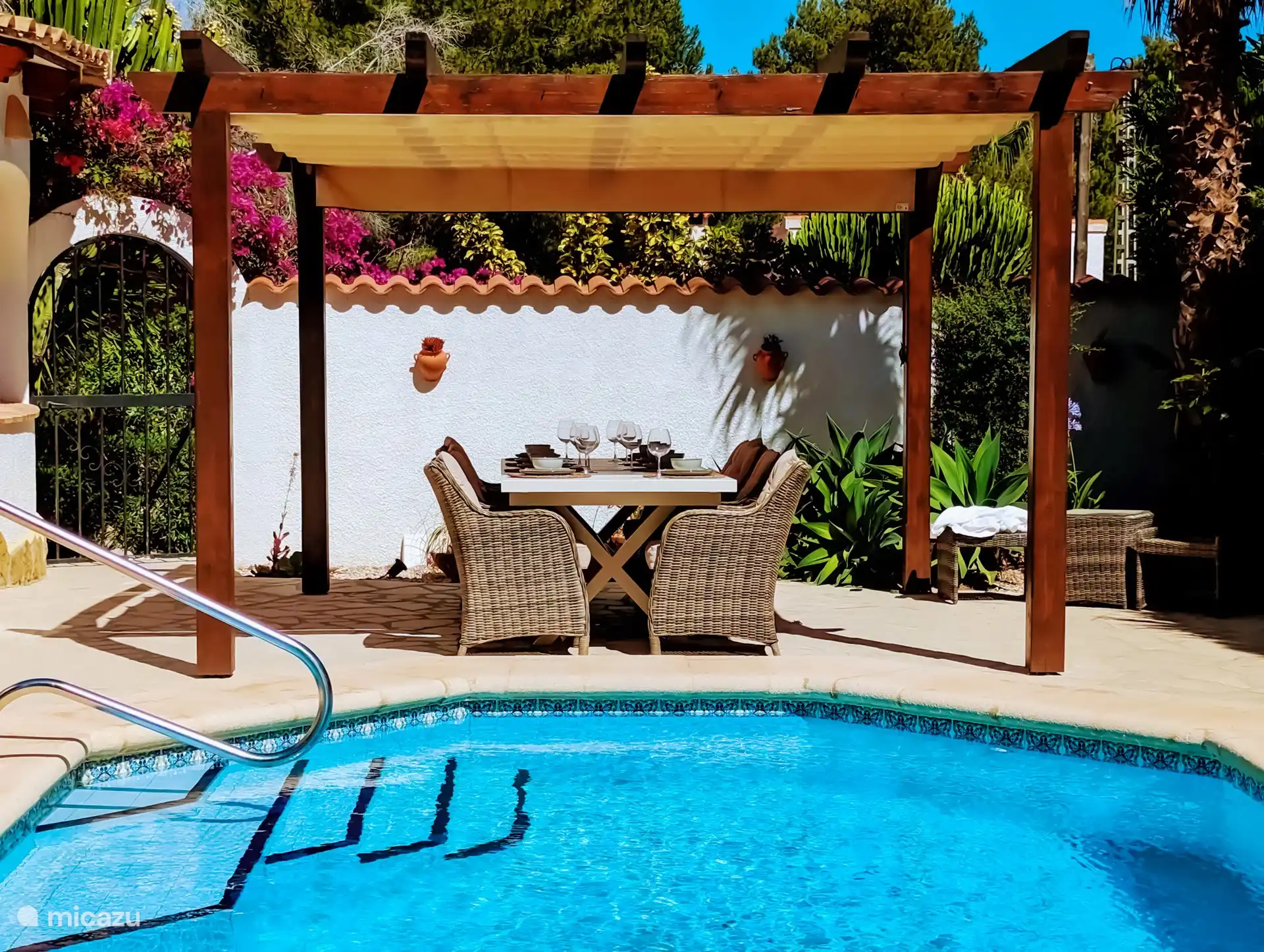 Eine Pergola mit Sonnendach bietet Platz für einen langen Tisch von 3 Metern und acht Stühle.