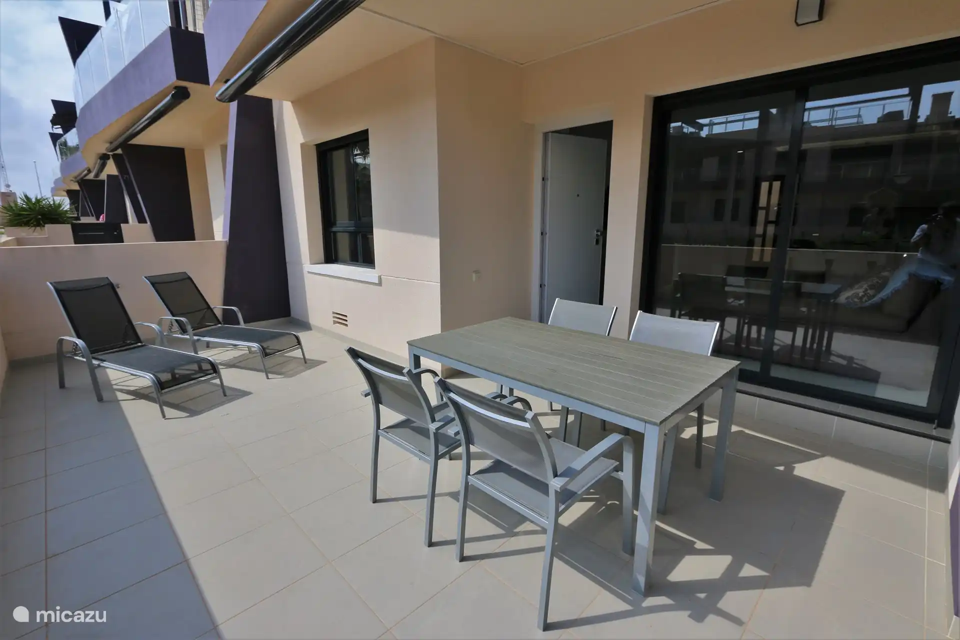 Balkon mit Esstisch und Liegestühlen