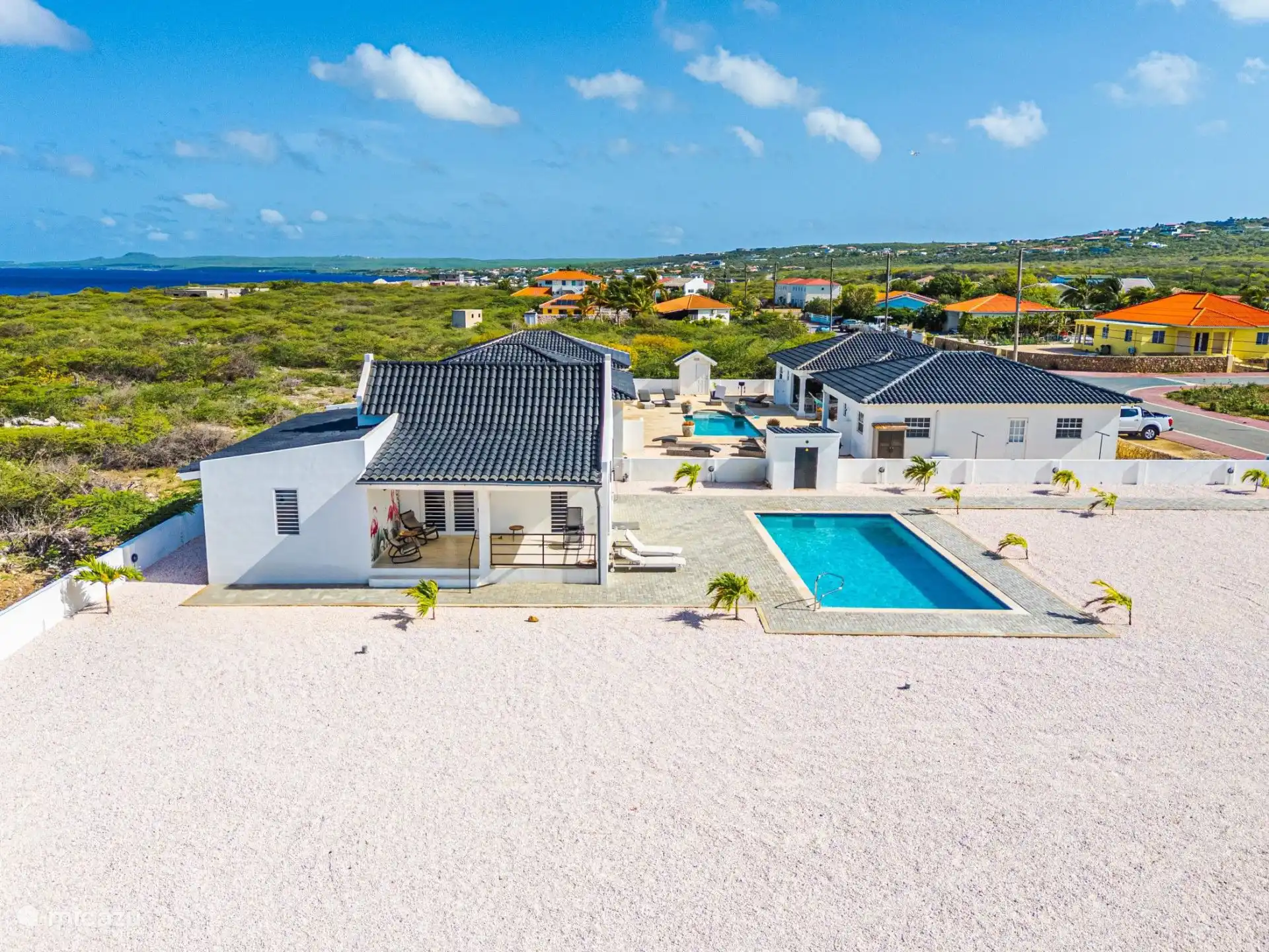 Zijkant van het huis, aan beide zijden een eigen terras. Het terras aan deze zijde zul je het meest gebruiken om te relaxen of om te eten of werken. Aan de andere zijde is de wasruimte, daar kun je oo