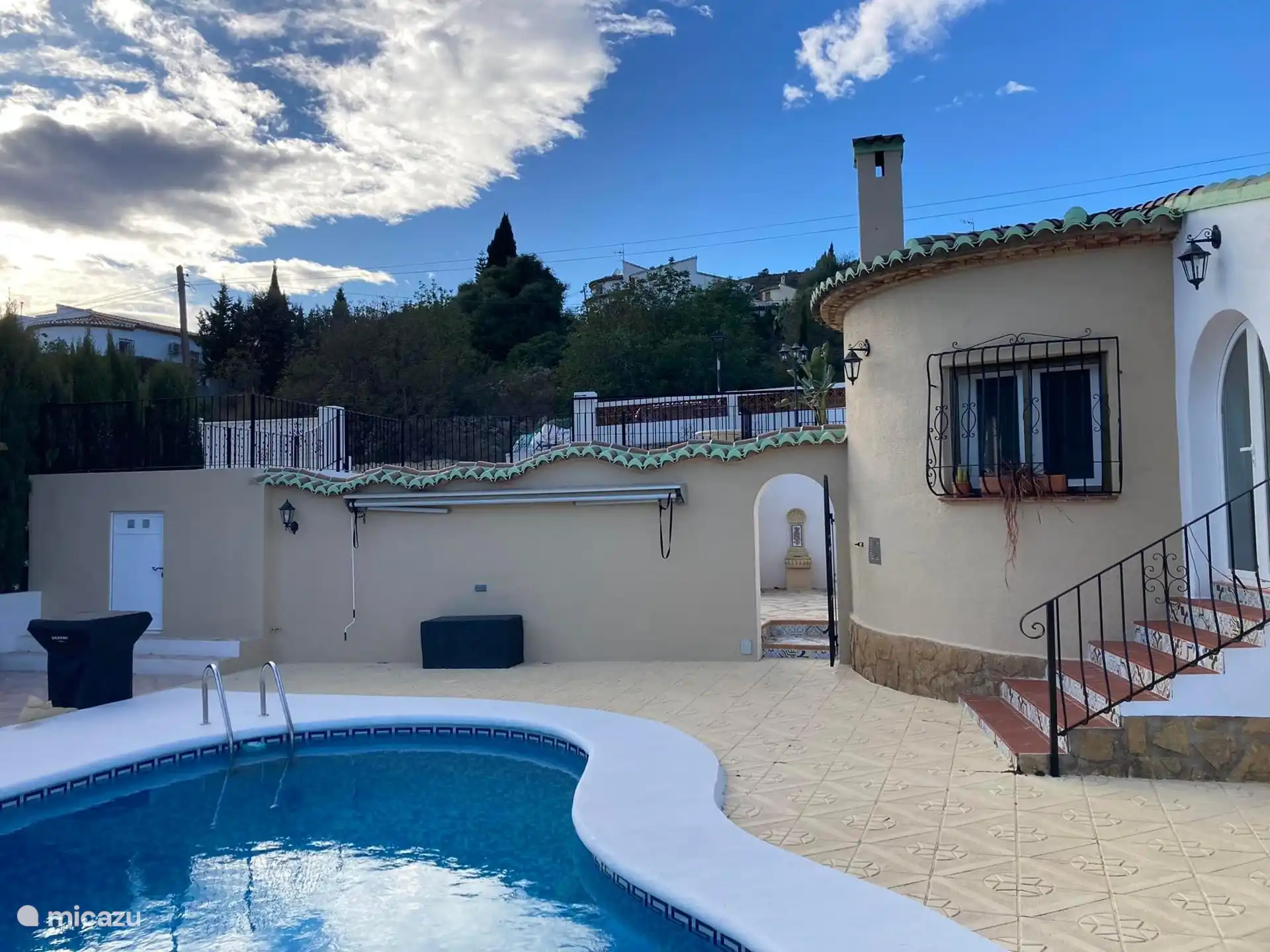 terrace behind the pool with a view of the parking deck and fence