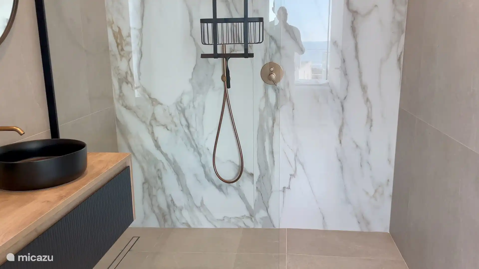 Badezimmer 1 mit begehbarer Dusche mit Marmorfliesen und Kupferarmaturen strahlt Luxus und Eleganz aus. 