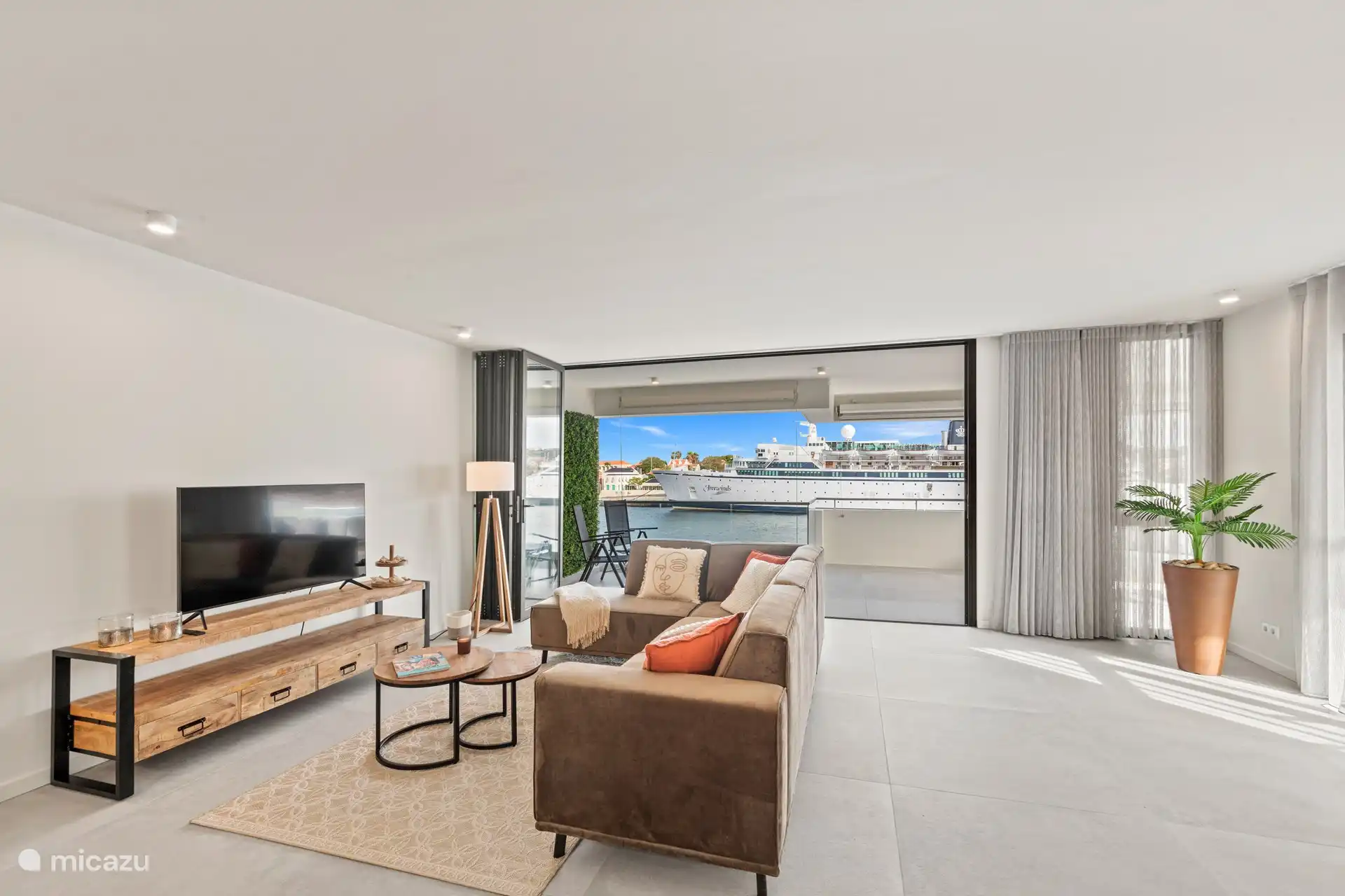 Geräumiges Wohnzimmer, das in den Balkon übergeht, mit offener Küche