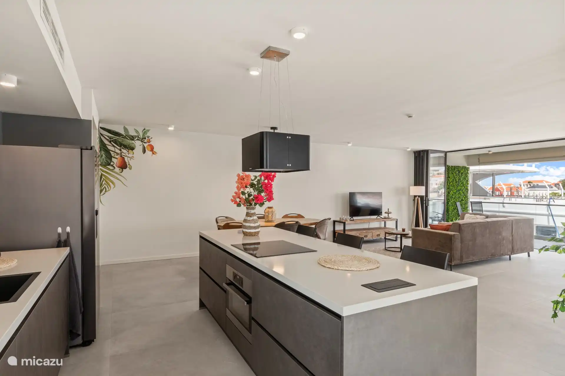 Offene Küche mit Kühlschrank mit Gefrierfach, Induktionsherd, Backofen und Geschirrspüler. 