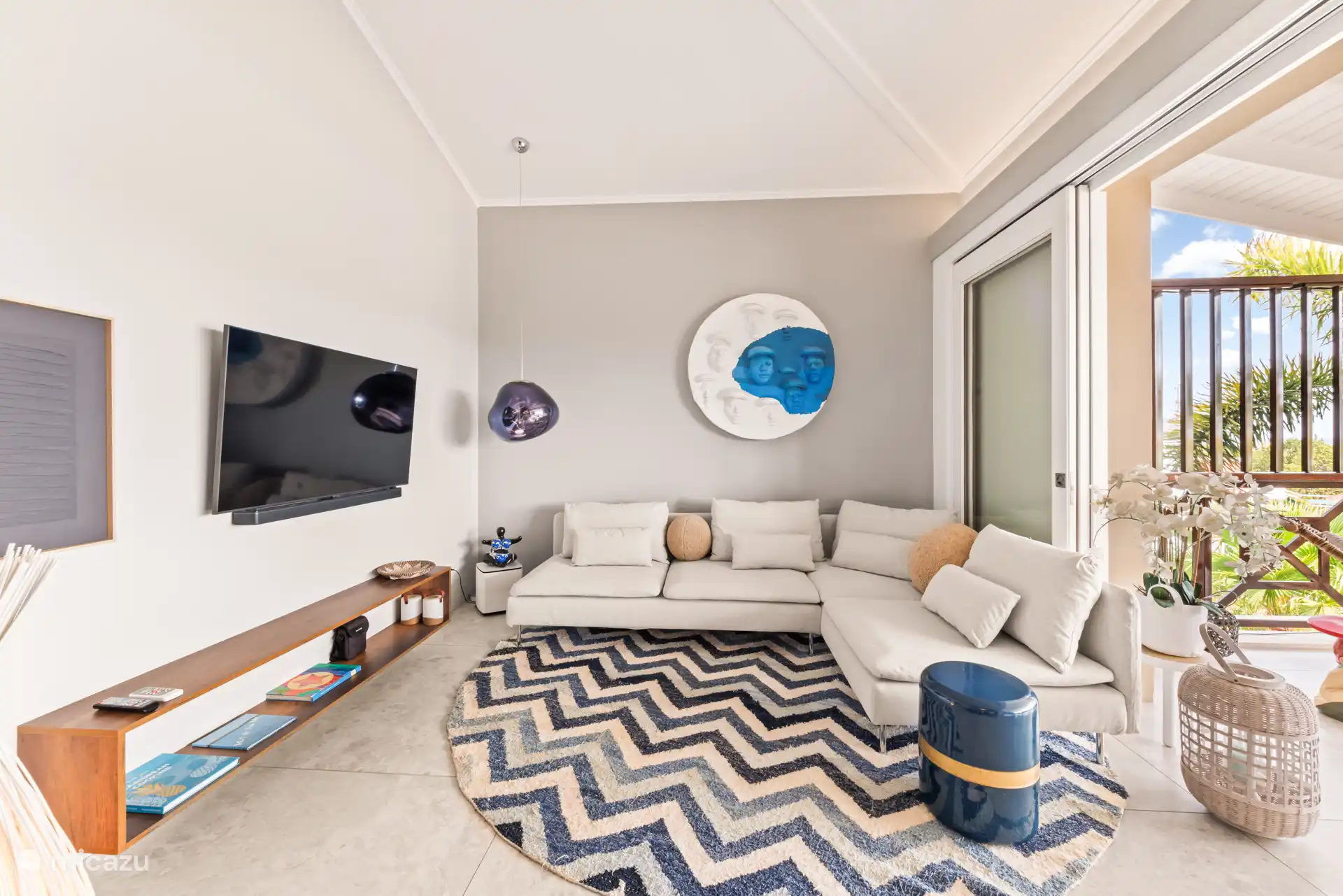 Salón con sofá lounge, smart TV y sistema Bose.