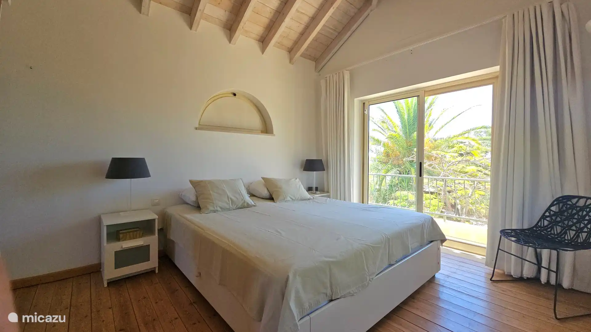 Schlafzimmer im 1. Stock mit eigenem Bad und Schiebetüren zu einem Südbalkon mit Blick auf den Garten, die Landschaft und das Meer im Hintergrund.