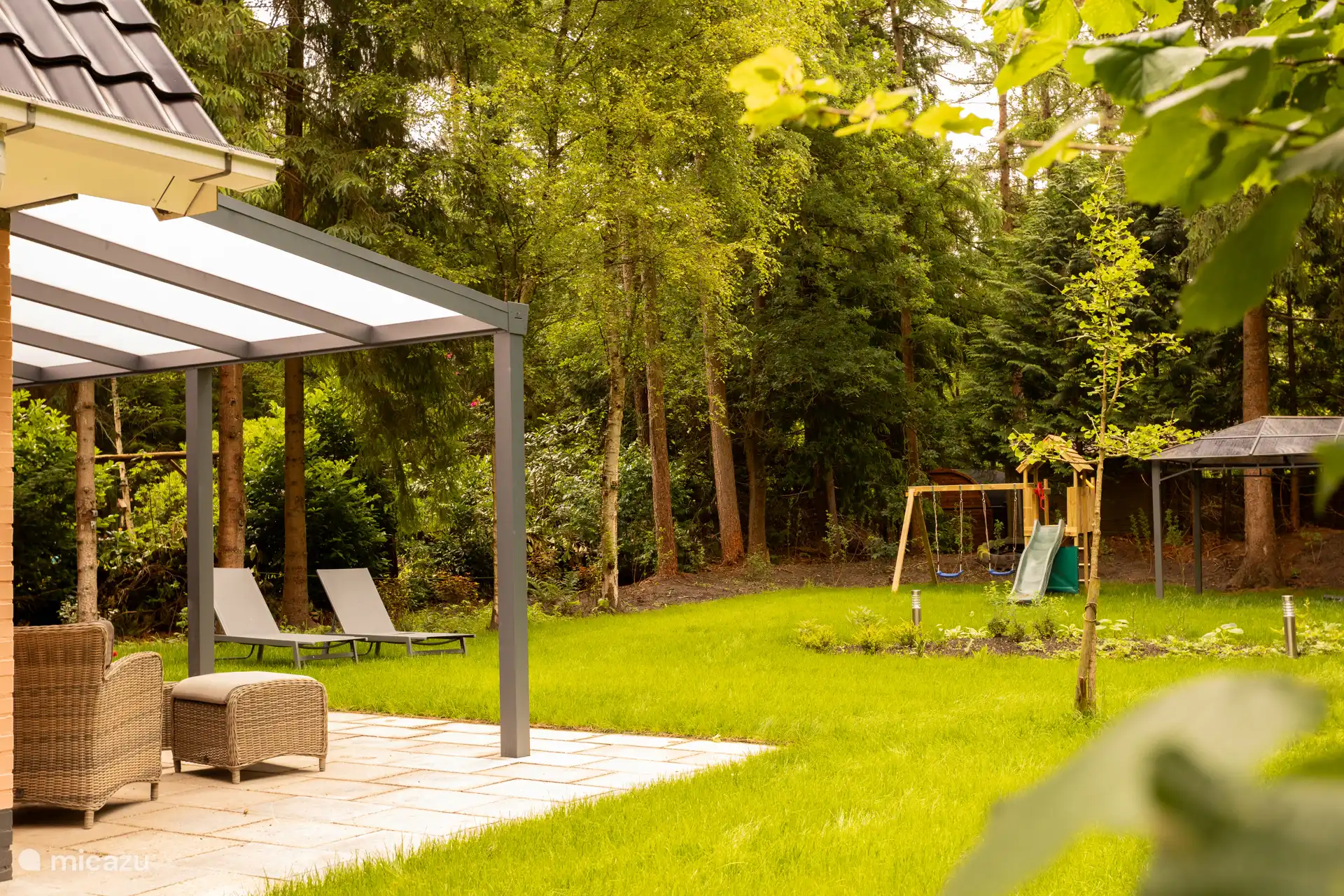 Im hinteren Teil des Gartens befindet sich ein Spielplatz für die Kleinen zum Klettern und Schaukeln und ein Vordach mit Sandkasten für zusätzlichen Spaß.