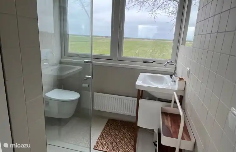 Das Badezimmer im Obergeschoss mit Toilette, Waschbecken und Regendusche sowie wunderschöner Aussicht