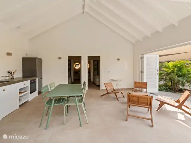 Villa Blenchi Curaçao Zwembad & Tuin huren in Curaçao, Curacao-Midden, Willemstad - vakantiehuis Lichte woonkeuken met eettafel, zithoek en toegang tot beide slaapkamers met aansluitende badkamers. Via de shutterdeuren stap je zo het terras en de tropische tuin in