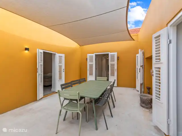 Stadsvilla Curaçao, Zwembad & Tuin huren in Curaçao, Curacao-Midden, Willemstad - vakantiehuis Sfeervolle binnenplaats met elegante smeedijzeren toegangspoort, zonneluifel en royale eettafel – een intieme plek om buiten te genieten