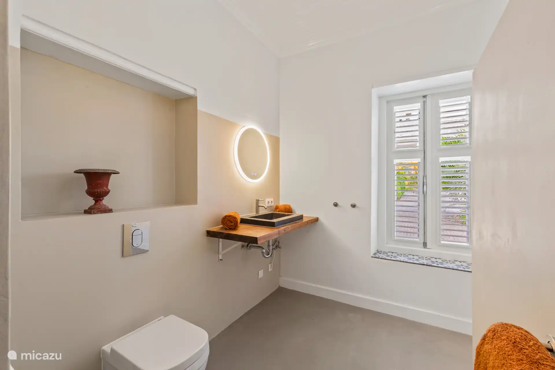 Bright bathroom with natural stone sink, designer lighting and a view of the tropical garden