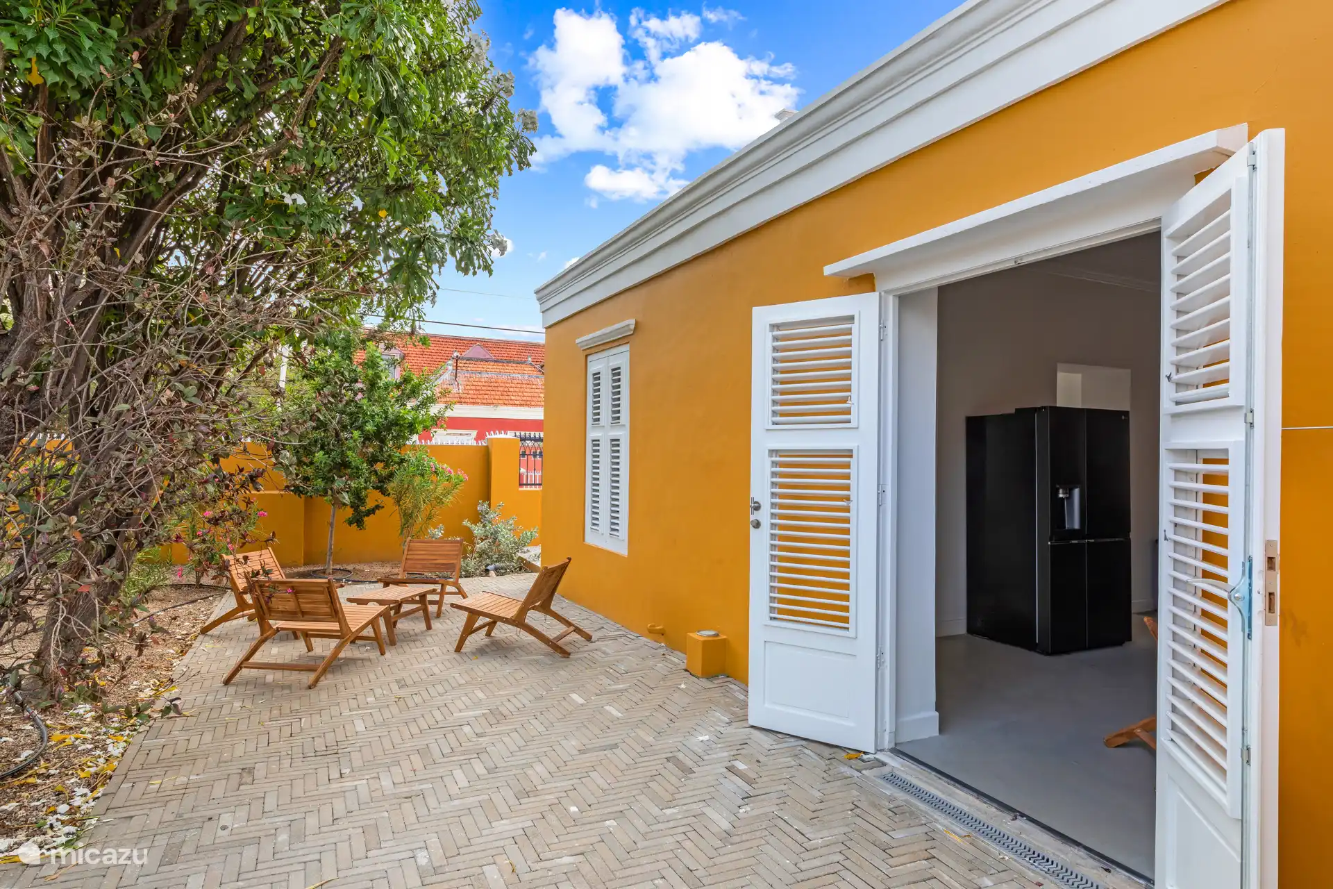 Charming side terrace with attractive seating under the tropical trees, ideal for relaxing moments in the lee of the city